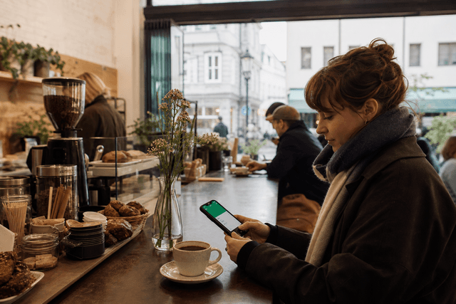 Tresen in einem kleinen Café mit Tasse Filterkaffee und Smartphone, auf dem eine Wallet-Karte sichtbar ist