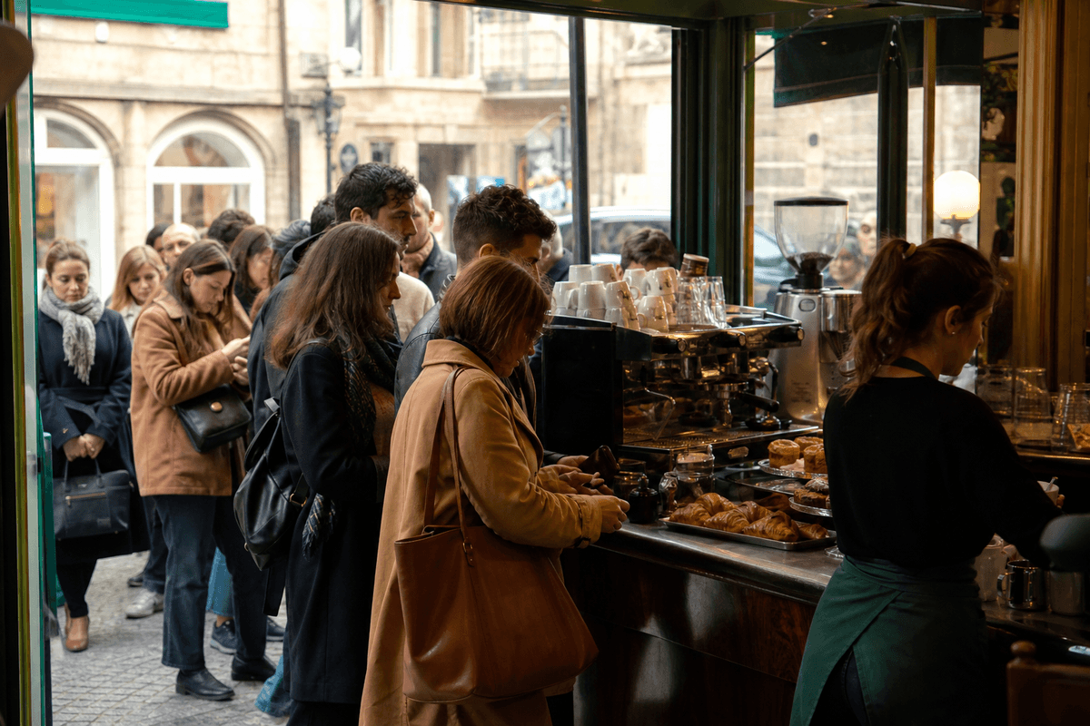 Comptoir d'un café parisien en heure de pointe matinale avec une file de clients