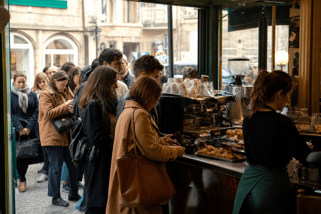 Comptoir d'un café parisien en heure de pointe matinale avec une file de clients