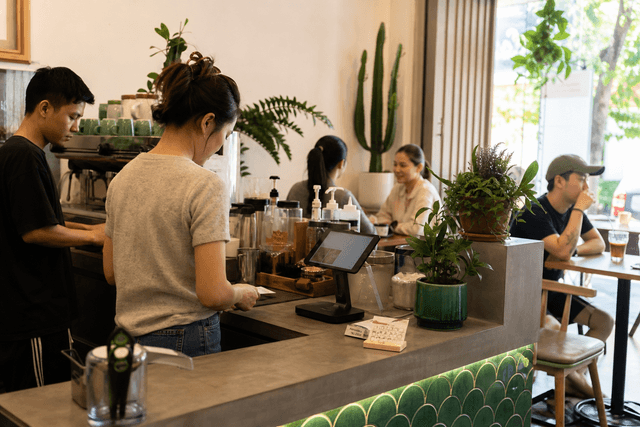 Quầy pha chế của một quán cà phê Việt độc lập với menu viết tay và thẻ tích điểm giấy nằm cạnh máy POS